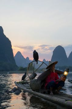 a woman sitting on top of a boat holding a lantern