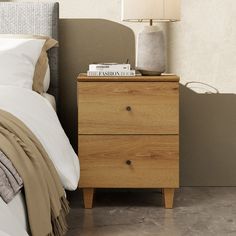 a nightstand with a book on top of it next to a night stand and lamp