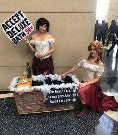 two women dressed up as witches and one holding a sign