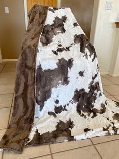 a cow print blanket sitting on top of a tiled floor