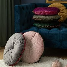 a blue couch with pillows on top of it in front of a painting and two slippers