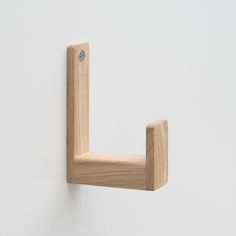 a wooden hook is attached to a white wall with a light blue button on it