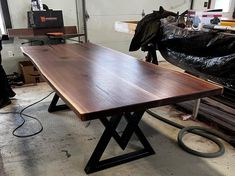 a large wooden table sitting inside of a room next to a black trash bag and other items