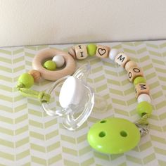 a green pacifier sitting on top of a table next to a baby pacifier