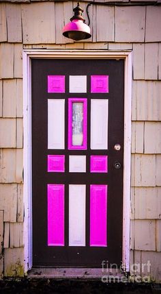 a pink and black door with a light on it's sidelight in front of a house