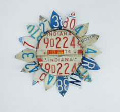 a clock made out of license plates with numbers on it's face and in the shape of a sunburst