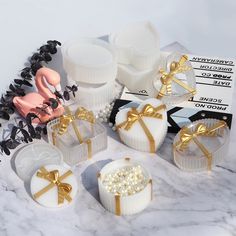 a table topped with white cakes covered in frosting and gold ribboned bowknots