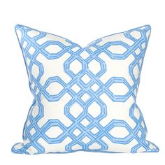 a blue and white pillow with an interlocked design on the front, sitting on a table