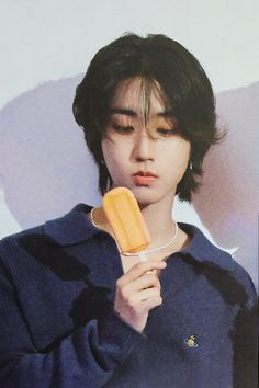 a young man holding an orange popsicle in his hand