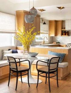 a dining room table with chairs and a vase on the table in front of it