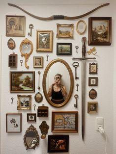 a woman taking a selfie in front of a wall full of pictures and mirrors