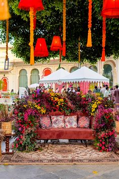 an outdoor seating area decorated with flowers and lanterns