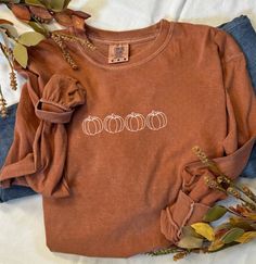 Fall Pumpkin Burnt Orange Comfort Colors Long Sleeve Shirt Welcome autumn with cozy style in our Fall Pumpkin Burnt Orange Comfort Colors Long Sleeve Shirt. Designed for both comfort and seasonal flair, this shirt is perfect for crisp fall days, pumpkin patch adventures, and festive gatherings. Key Features: Festive Design: Features a delightful pumpkin graphic with intricate autumn details, capturing the essence of fall. The design adds a touch of whimsy and seasonal charm, making it a must-hav Casual Brown T-shirt For Fall, Brown Long Sleeve Cotton T-shirt, Cozy Orange Crew Neck Top, Cozy Long Sleeve Cotton Tops, Trendy Cozy Fit Tops For Fall, Comfortable Long Sleeve Brown Top, Fall Long Sleeve Relaxed Fit T-shirt, Cute Long Sleeve Orange Top, Cozy Fit Long Sleeve Cotton Top