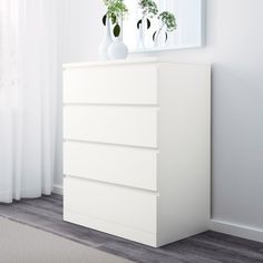 a white dresser with three vases on top of it