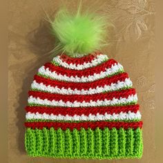 a crocheted hat with a green pom - pom sitting on top of it