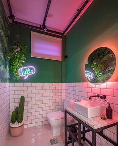 a bathroom with two sinks, a toilet and a cactus plant in the corner on the wall