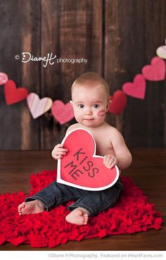 a baby is holding a heart shaped sign