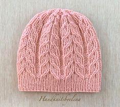 a pink knitted hat on top of a wooden table