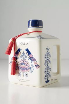 a white jug with blue and red birds painted on the side, holding a tassel