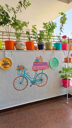 there are many potted plants on the side of this wall with a bike painted on it