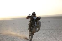 a man riding on the back of a dirt bike in the middle of the desert