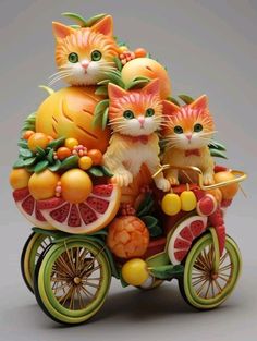 a figurine of three cats riding on top of a bike with fruit and vegetables