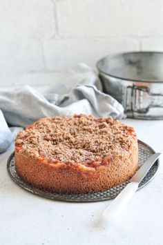 a cake sitting on top of a metal plate next to a pan with a knife