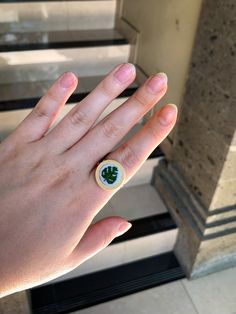 a person's hand with a green and white ring on top of their finger