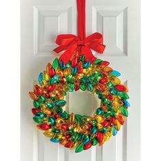 a christmas wreath hanging on a door with a red bow around it and lights in the middle