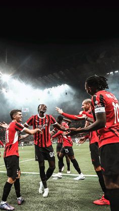 a group of men standing on top of a soccer field holding hands in the air