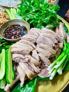 a plate full of meat and vegetables with sauce on the side, along with other food items