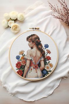 a cross stitch pattern with a woman in a white dress and flowers on the table