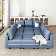 a large blue couch sitting in a living room next to a window