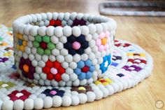 a white bracelet with multicolored beads on it sitting on top of a wooden table