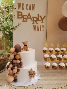 a three tiered cake with teddy bears on top and cupcakes in the background