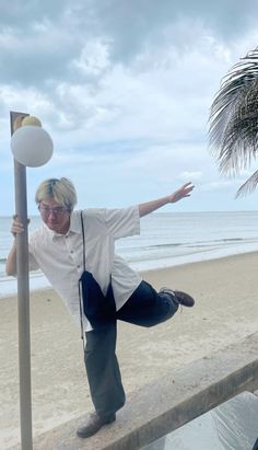 a man leaning against a pole on the beach