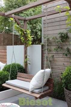 a wooden bench sitting on top of a white tile floor next to a green bush