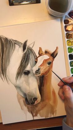 a person is painting a horse with watercolors on the table next to it