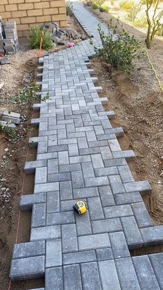 a walkway made out of cinder blocks with a yellow toy car on the ground next to it