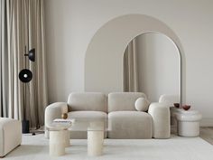 a white couch sitting in the middle of a living room next to a round mirror