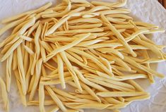 a white plate topped with lots of yellow pasta noodles on top of a wooden table