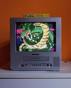 an old tv sitting on top of a white dresser next to a wall with orange walls