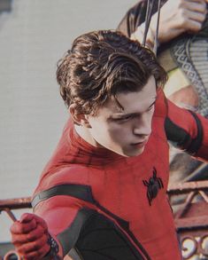 a young man dressed as spider - man in front of a building with other people