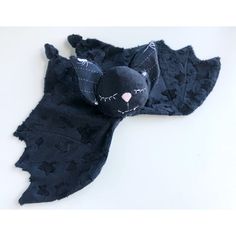 a black bat stuffed animal laying on top of a white surface