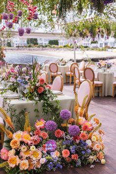 an outdoor dining area with tables and chairs covered in floral arrangements, hanging from the ceiling