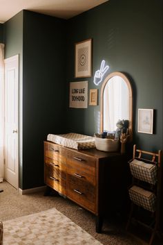 a bedroom with dark green walls and white trim on the wall, along with a wooden dresser