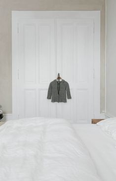 an unmade bed in a bedroom with white walls and closets on the wall