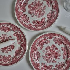 two red and white plates sitting on top of a table with utensils next to them