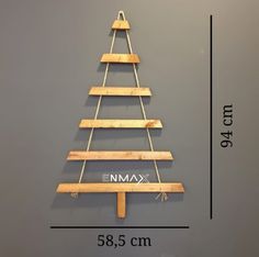 a wooden christmas tree hanging on a wall next to a measuring tape and a ruler