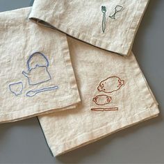 three tea towels with embroidered pictures on them